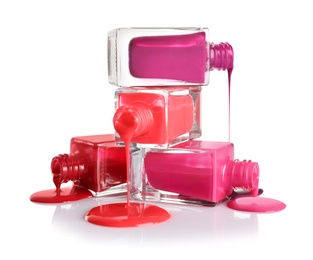 Photo of Spilled different nail polishes with bottles on white background