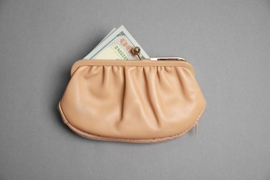 Photo of Stylish beige leather purse with dollar banknotes on light grey background, top view