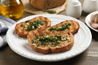 Photo of Tasty bruschettas with oil and garlic on wooden table, closeup