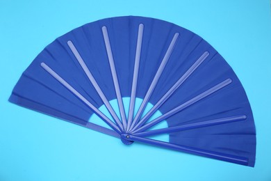 Photo of Bright color hand fan on light blue background, top view