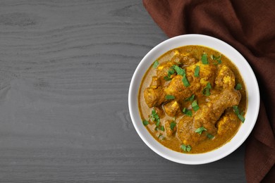 Photo of Delicious chicken with curry sauce on grey wooden table, top view. Space for text