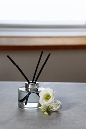 Photo of Reed diffuser and eustoma flowers on gray marble table