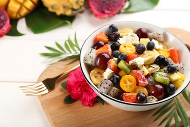 Photo of Delicious exotic fruit salad served on white table. Space for text