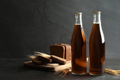 Bottles of delicious fresh kvass, spikelets and bread on grey table. Space for text