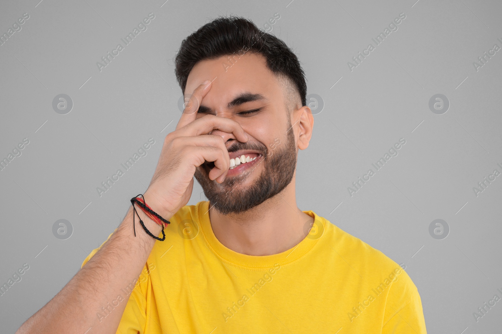 Photo of Handsome young man laughing on grey background