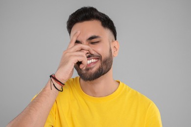 Photo of Handsome young man laughing on grey background