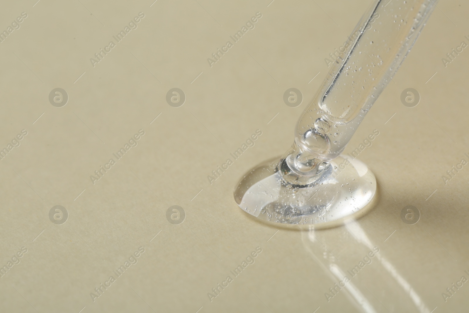 Photo of Pipette with cosmetic serum on beige background, closeup. Space for text