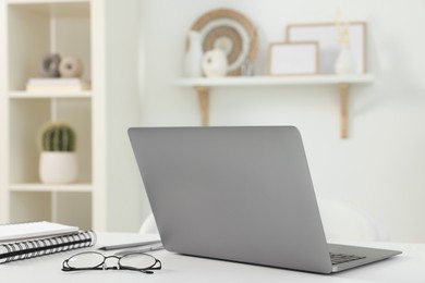 Home office. Laptop, glasses and stationery on white desk indoors