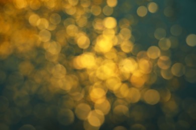 Photo of Blurred view of golden glitter on green background. Bokeh effect