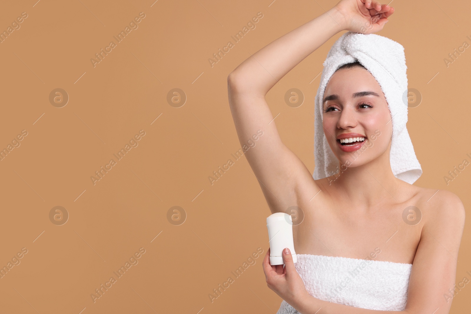 Photo of Beautiful woman applying deodorant on beige background, space for text