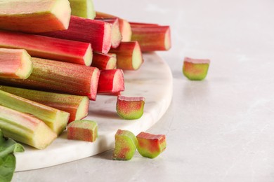 Whole and cut rhubarb stalks on white table, closeup. Space for text