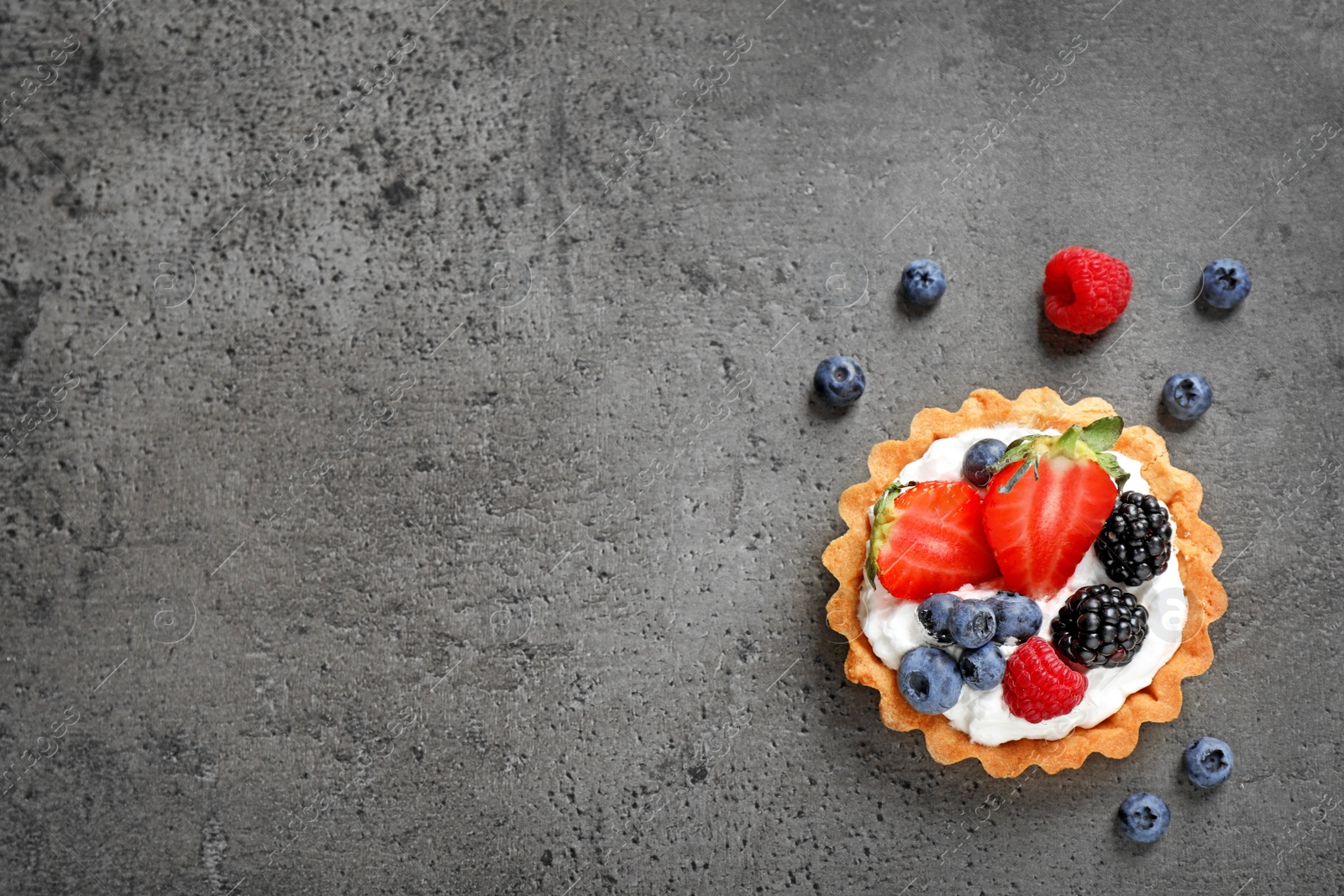 Photo of Tart with different berries on grey table, top view with space for text. Delicious pastries