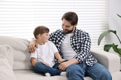Happy dad and son spending time together on sofa at home