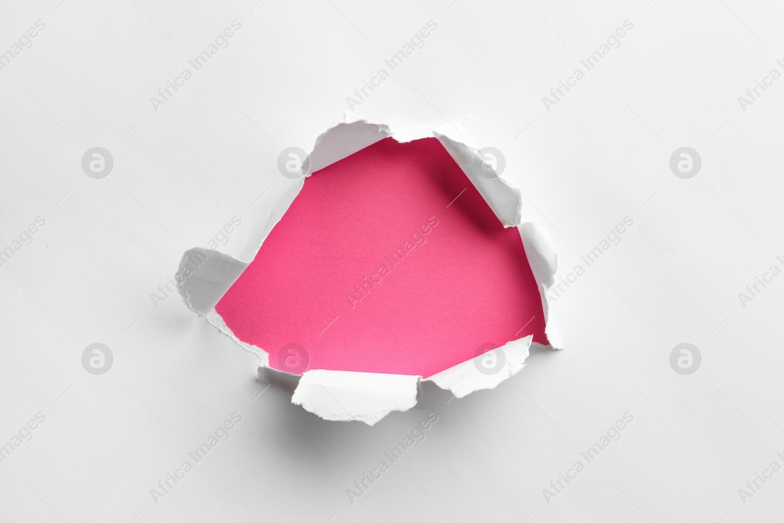 Photo of Hole in white paper on pink background