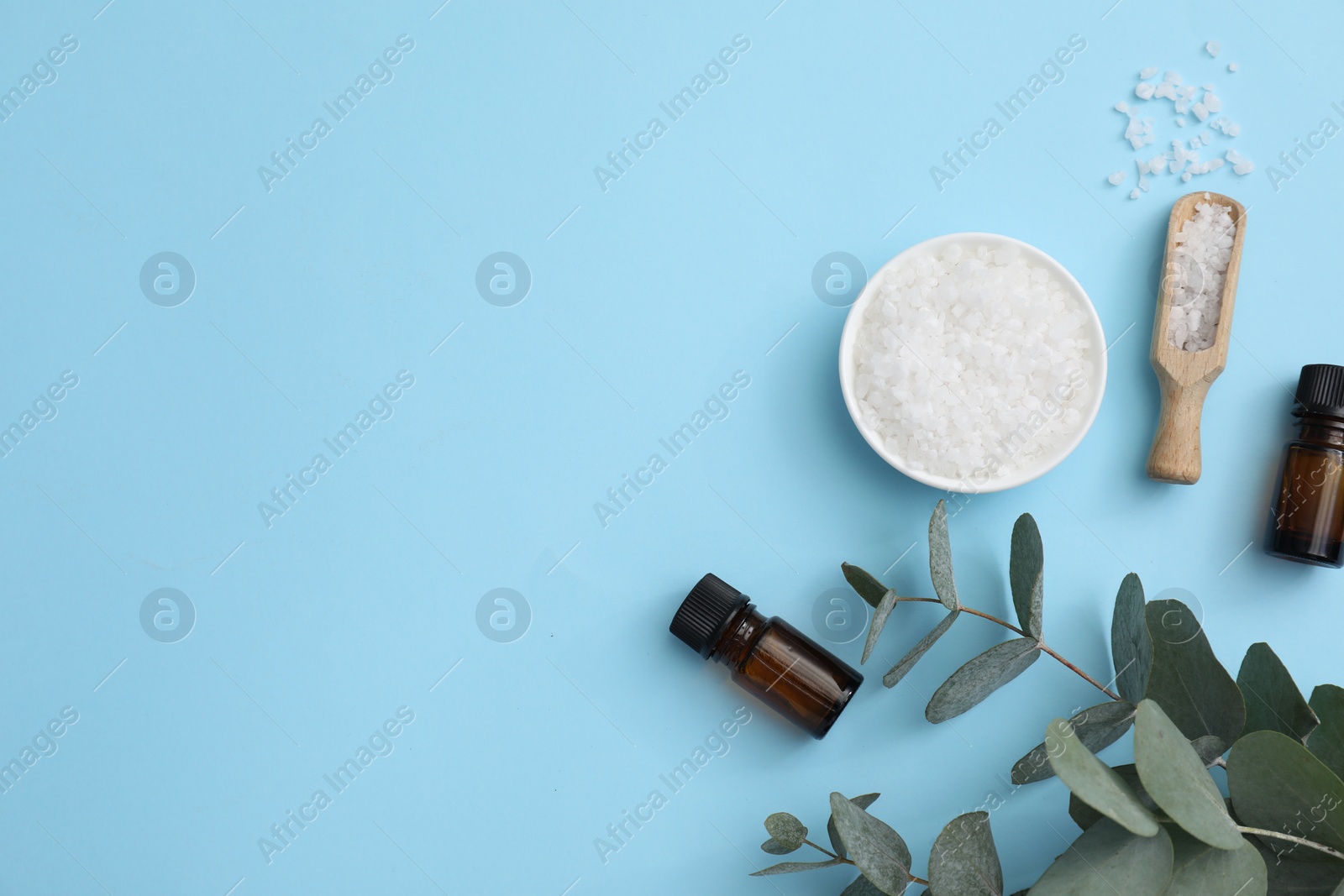 Photo of Aromatherapy products. Bottles of essential oil, sea salt and eucalyptus leaves on light blue background, flat lay. Space for text