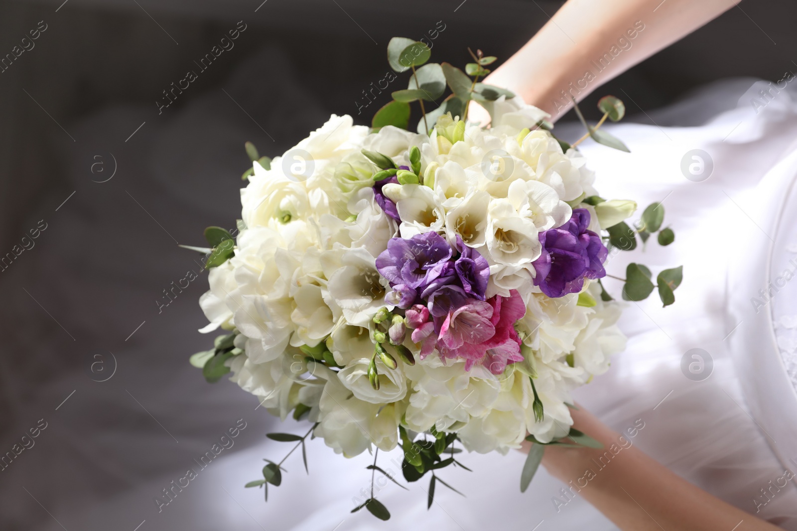 Photo of Bride holding beautiful bouquet with spring freesia flowers, closeup