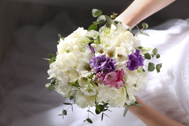 Photo of Bride holding beautiful bouquet with spring freesia flowers, closeup