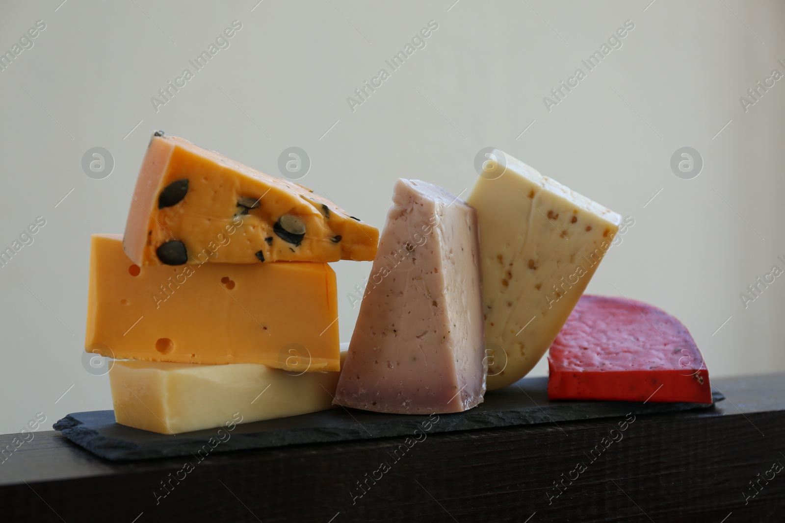 Photo of Different types of delicious cheeses on slate plate, closeup