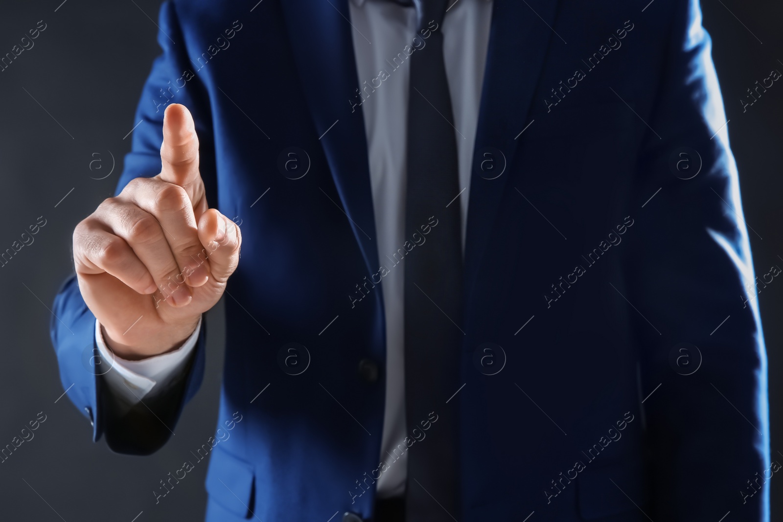 Photo of Businessman touching empty virtual screen against dark background, focus on hand