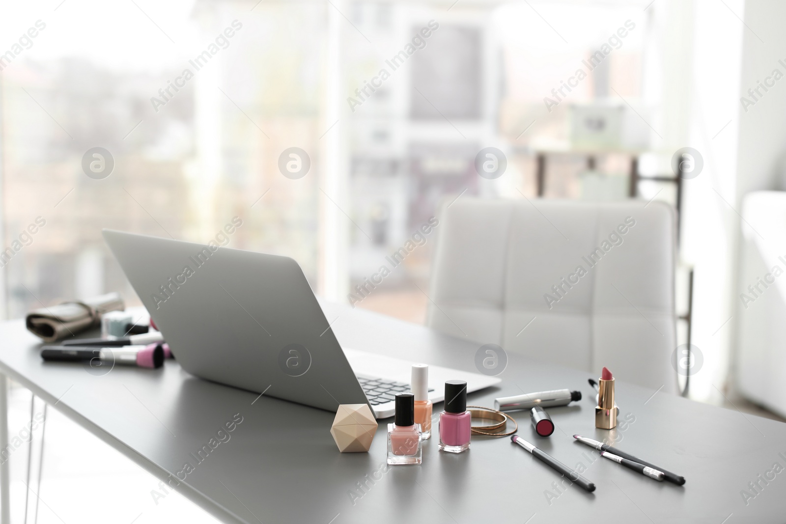 Photo of Makeup products for woman and laptop on table