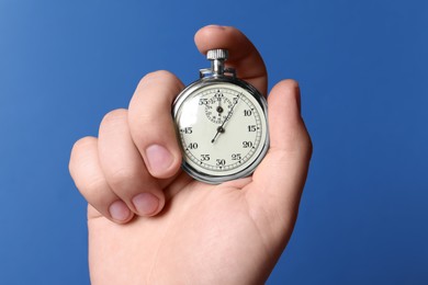 Photo of Man holding vintage timer on blue background, closeup