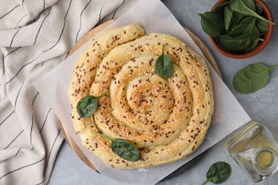 Photo of Delicious puff pastry with spinach on grey table, flat lay