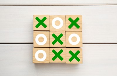 Photo of Tic tac toe cube set on white wooden table, flat lay