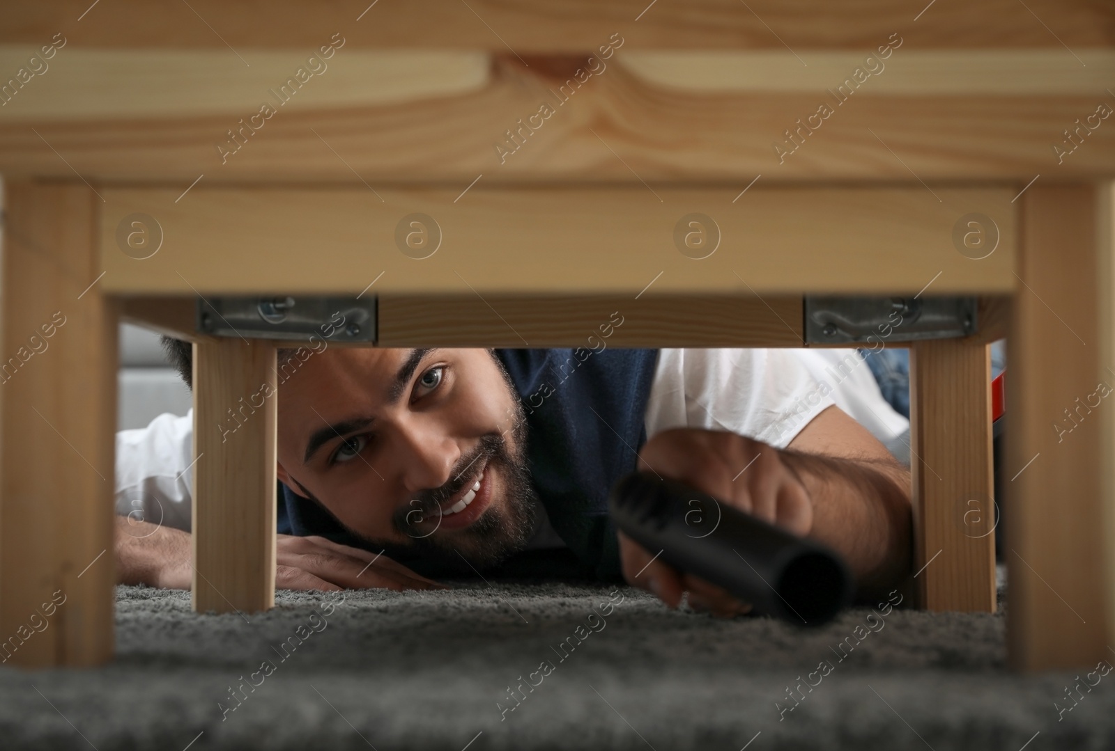 Photo of Young man using vacuum cleaner at home