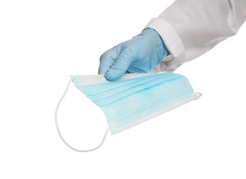 Photo of Doctor in latex gloves holding disposable face mask on white background, closeup. Protective measures during coronavirus quarantine