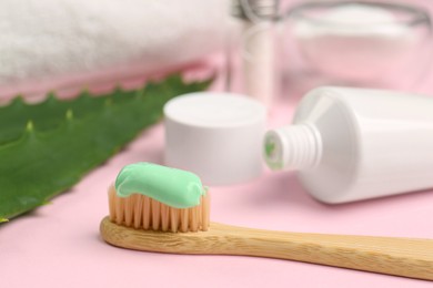 Toothbrush with aloe toothpaste on pink background, closeup