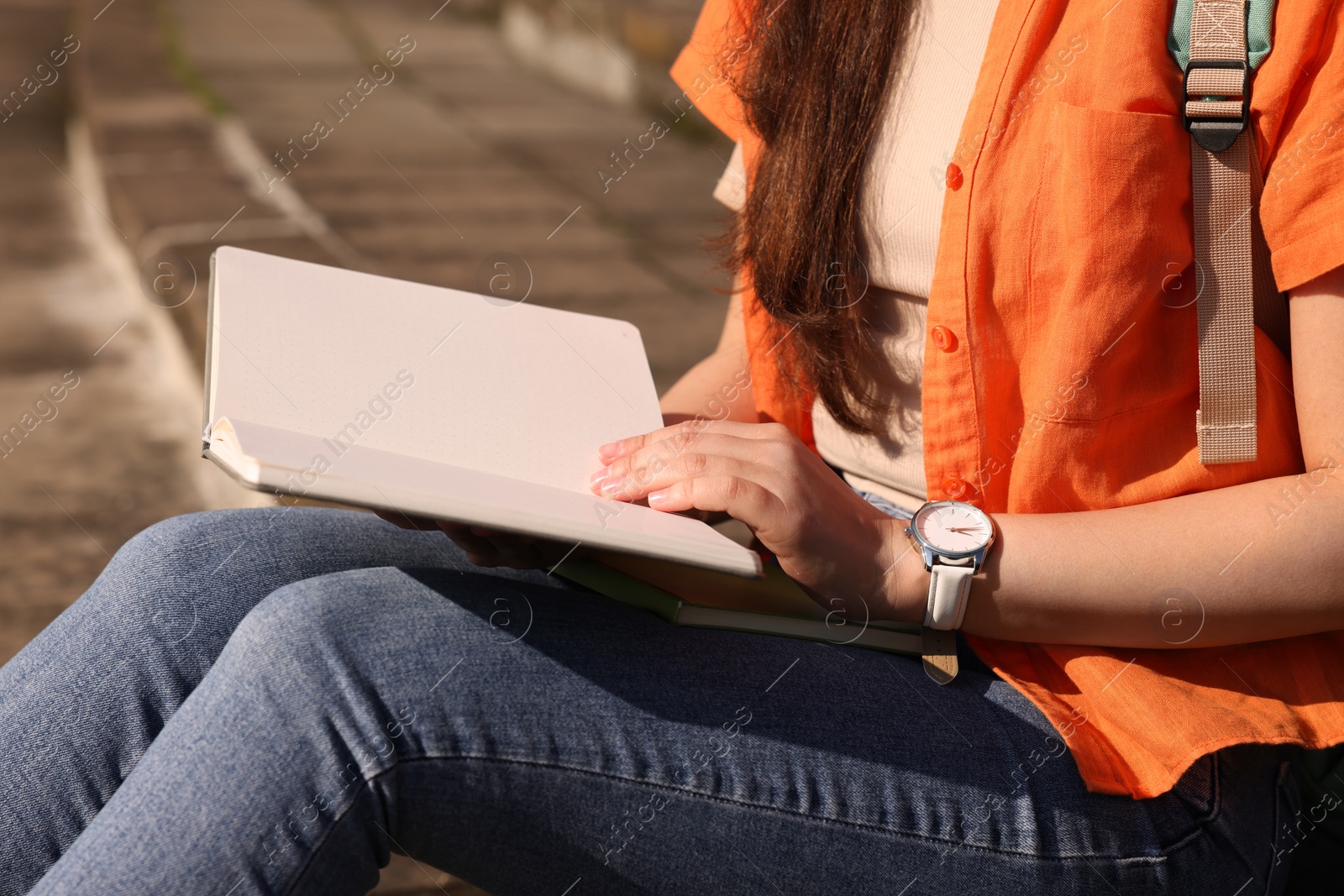 Photo of Student studying with notebook on steps outdoors, closeup