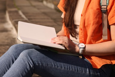 Photo of Student studying with notebook on steps outdoors, closeup