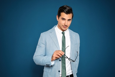 Portrait of handsome young man in suit on blue background