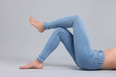 Woman wearing stylish jeans on light gray background, closeup