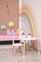 Photo of Cute child's room interior with beautiful rainbow painted on wall