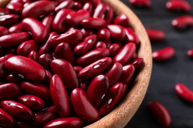 Photo of Raw red kidney beans in wooden bowl on table, closeup