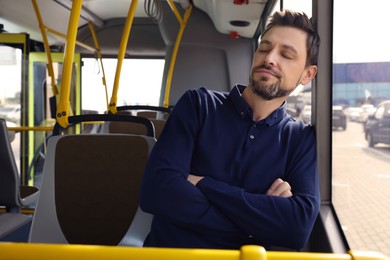 Tired man sleeping while sitting in public transport