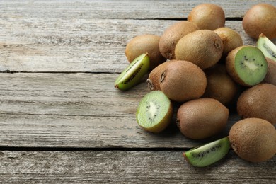 Pile of fresh ripe kiwis on wooden table, space for text