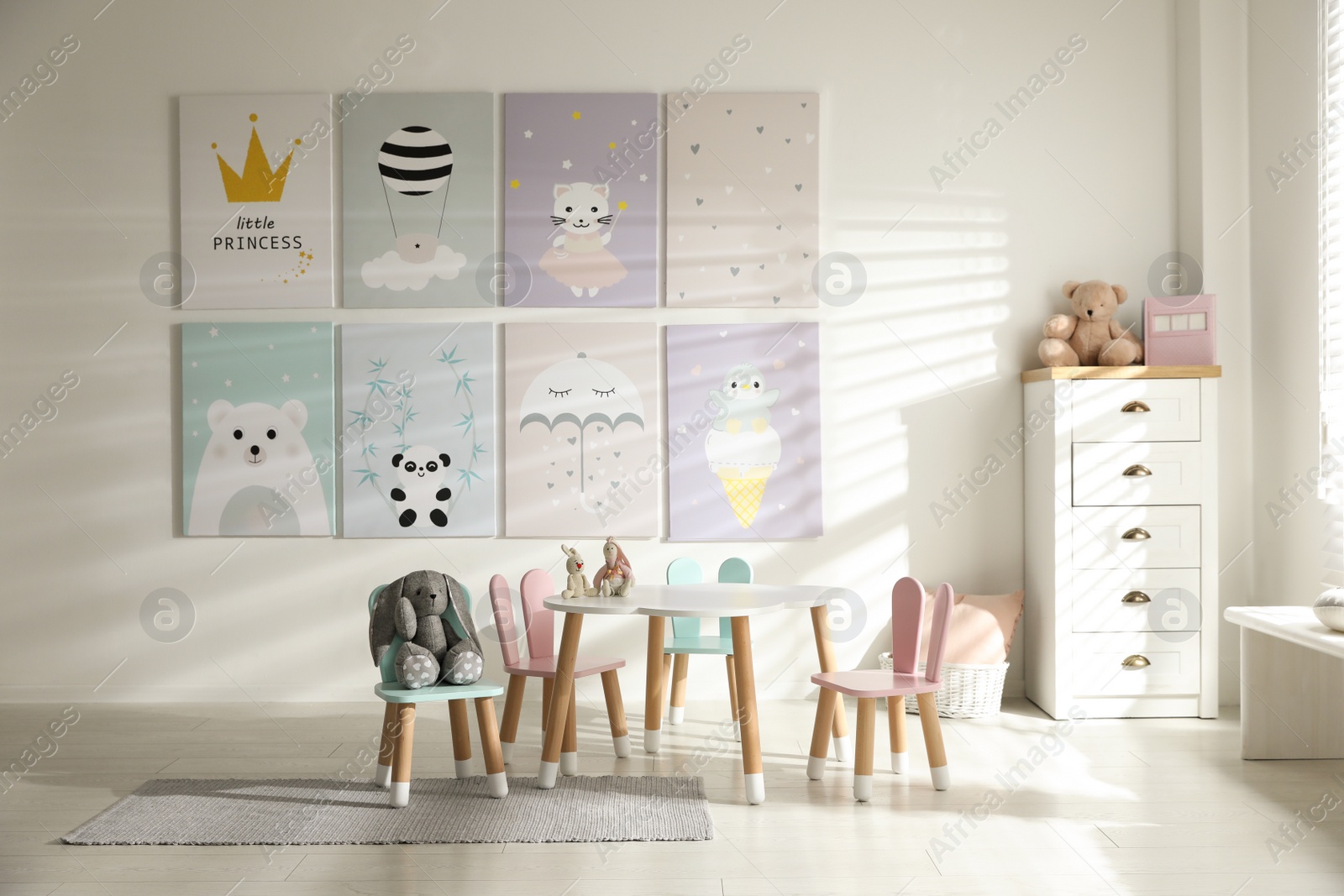 Photo of Small table and chairs with bunny ears in children's room interior