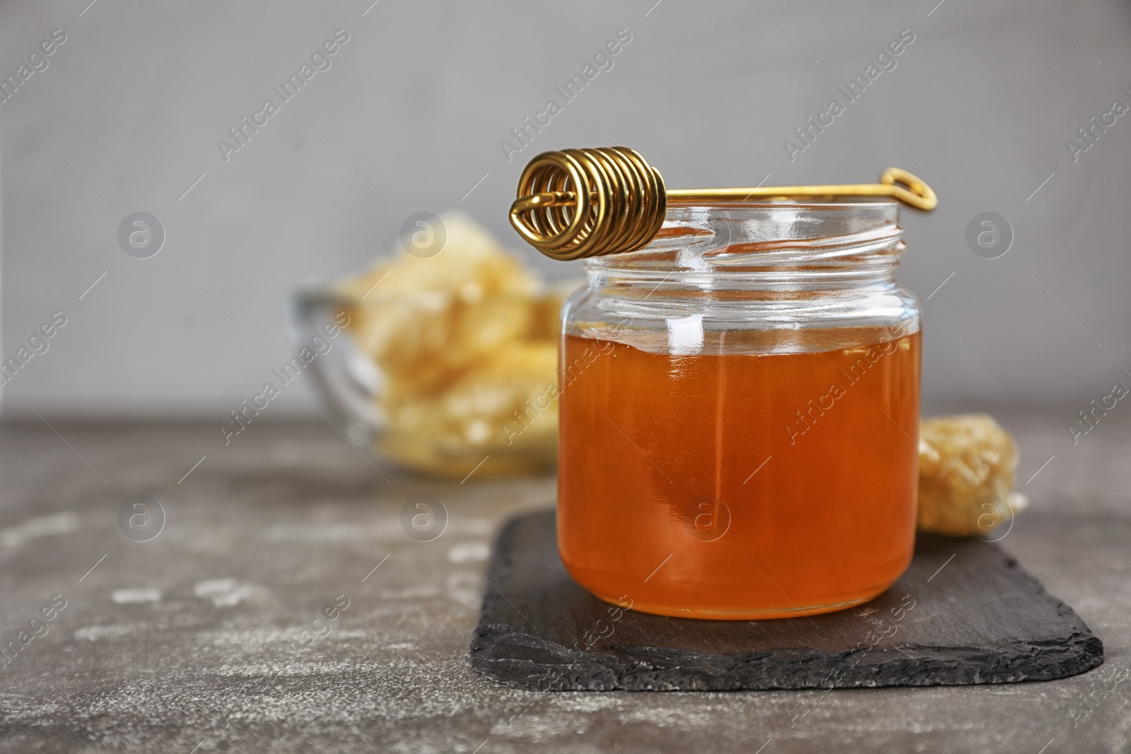 Photo of Jar of honey and dipper on table