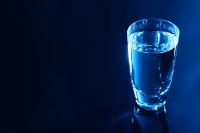 Photo of Glass of vodka on dark table, space for text