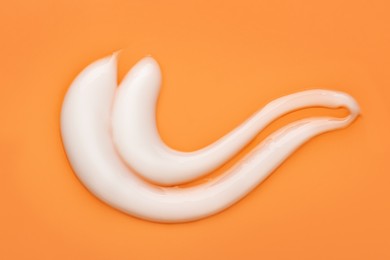 Photo of Body cream sample on orange background, closeup. Cosmetic product