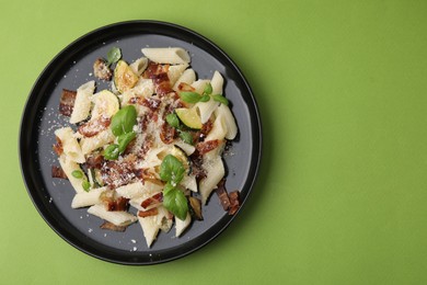 Photo of Tasty pasta with bacon and basil on light green table, top view. Space for text