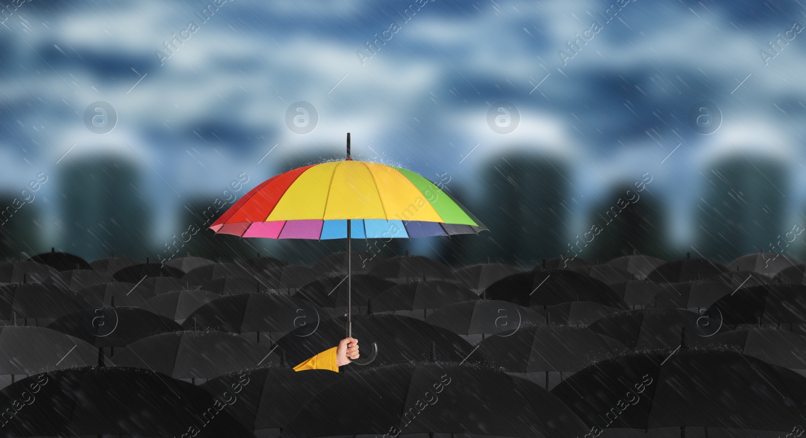 Image of Person holding umbrella over other under heavy rain outdoors 