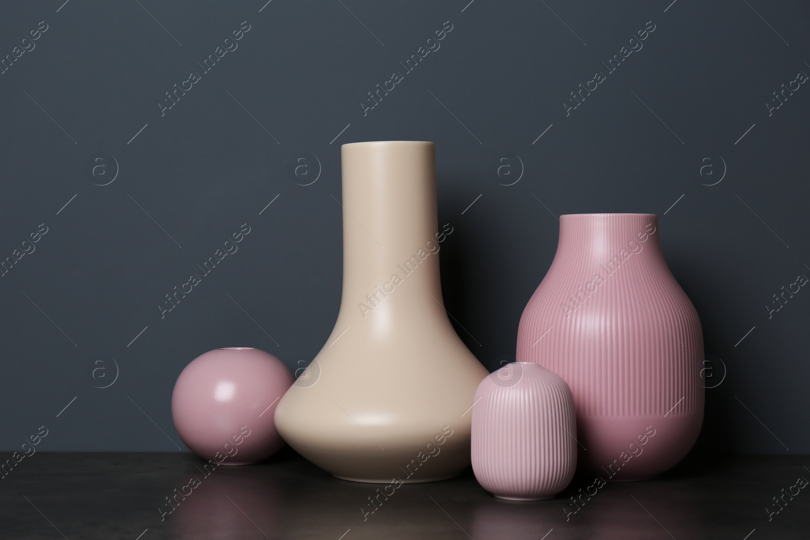 Photo of Beautiful ceramic vases on table against color wall