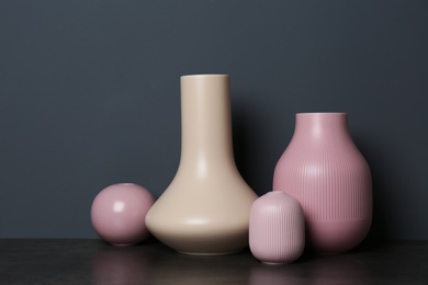 Beautiful ceramic vases on table against color wall