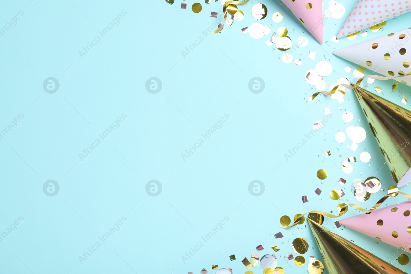 Photo of Flat lay composition with party hats and confetti on light blue background, space for text. Birthday items