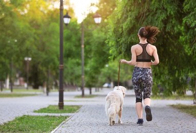 Photo of Young woman with her dog together in park. Pet care