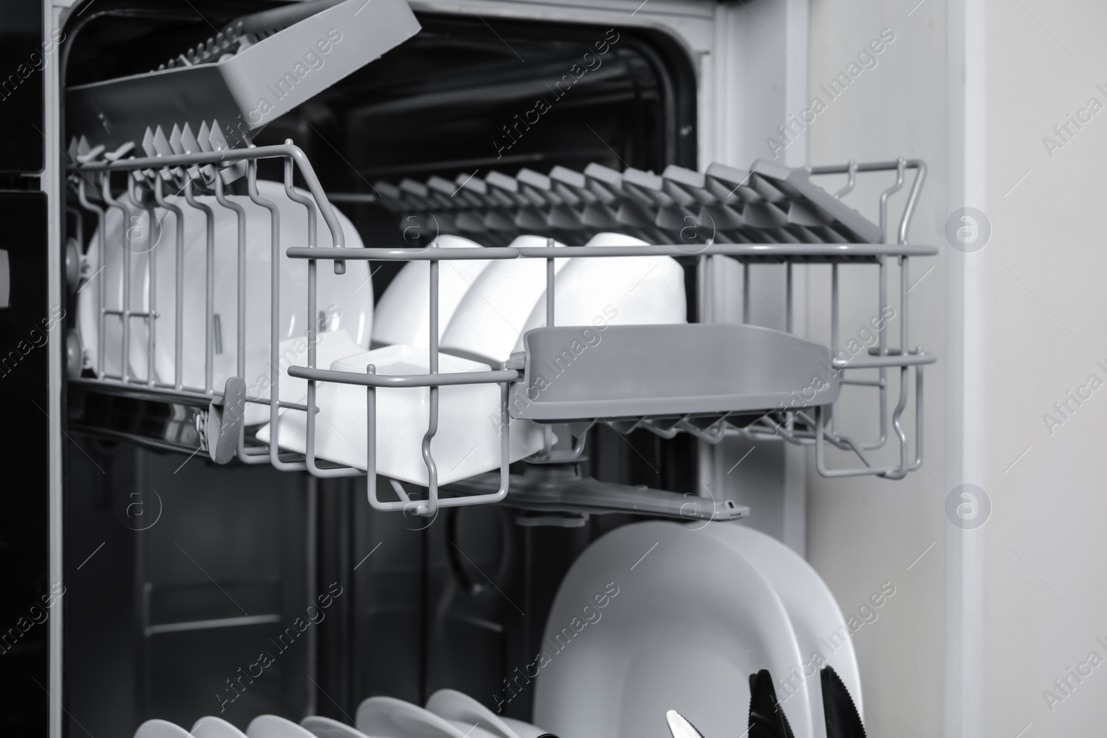 Photo of Open modern dishwasher with clean tableware, closeup