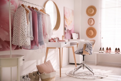 Dressing room interior with stylish makeup table, clothes and accessories